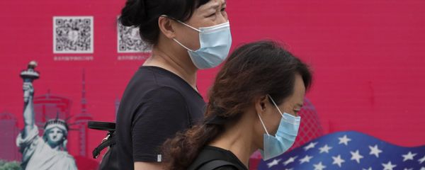 Женщины в защитных масках проходят мимо рекламного щита в Пекине - Sputnik Азербайджан