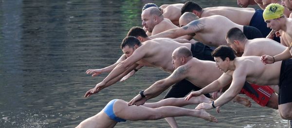 Мужчины прыгают в озеро, чтобы поймать деревянный крест во время празднования Дня Крещения в Софии, Болгария - Sputnik Азербайджан