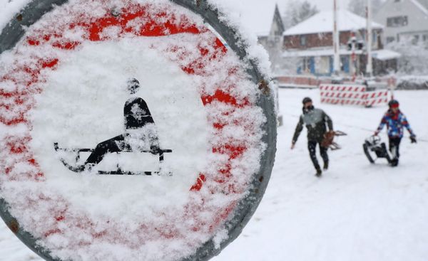 People carrying sledges walk past a snow covered traffic sign, as the spread of the coronavirus disease (COVID-19) continues, in Zurich, Switzerland January 12, 2021.  - Sputnik Азербайджан