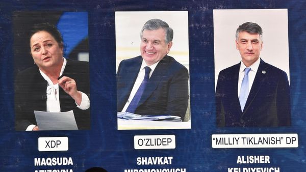 Люди проходят перед рекламным щитом с изображениями кандидатов в президенты Узбекистана - Sputnik Азербайджан