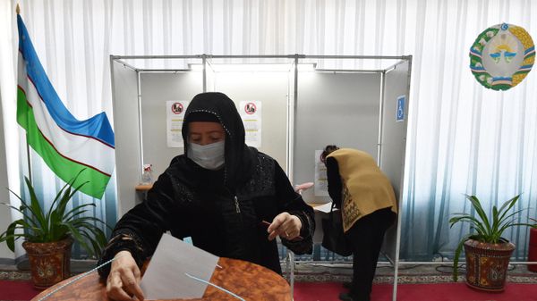 Женщина голосует на избирательном участке во время выборов президента Узбекистана - Sputnik Азербайджан