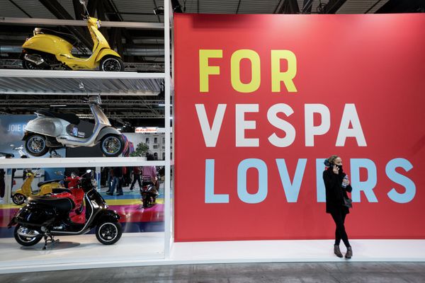 Женщина стоит рядом с моделями Piaggio Vespa, демонстрируемыми на EICMA. - Sputnik Азербайджан