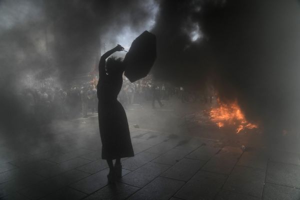 Демонстрантка с зонтиком в облаке дыма во время акции протеста против рефинансирования долга в 45 миллиардов долларов в Буэнос-Айресе, Аргентина. - Sputnik Азербайджан