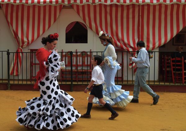 Люди в типичных севильских костюмах идут по улице во время фестиваля Feria de Abril в Севилье, Испания. - Sputnik Азербайджан