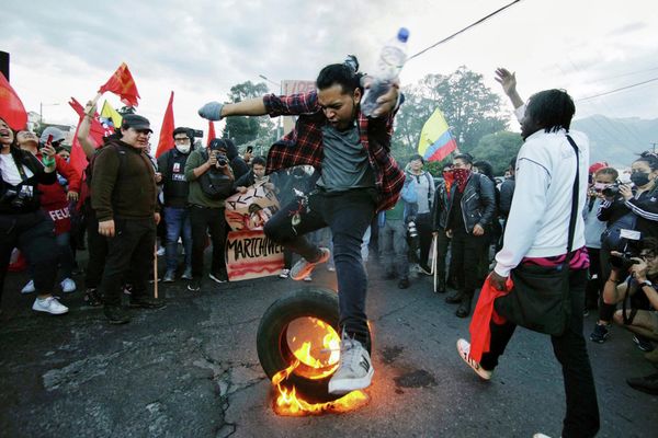 Студент прыгает через горящую покрышку во время демонстрации против правительства в Кито. - Sputnik Азербайджан
