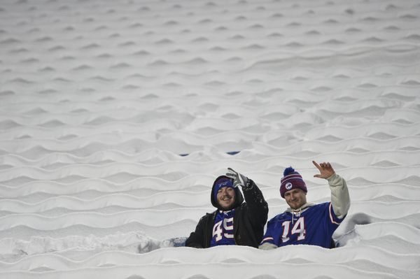 Фанаты Buffalo Bills сидят на заснеженных сиденьях во время разминки перед футбольным матчем между Buffalo Bills и Miami Dolphins в Орчард-парке, штат Нью-Йорк. - Sputnik Азербайджан