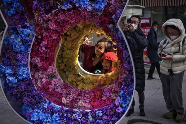 Женщина и ребенок позируют фотографируются перед цветочным орнаментом в виде кролика на пешеходной торговой улице в Цяньмэнь в первый день Лунного Нового года в Пекине. - Sputnik Азербайджан