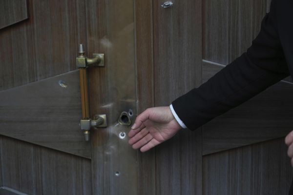 Мужчина показывает на пулевые отверстия, оставшиеся после нападения на посольство Азербайджана в Тегеране. - Sputnik Азербайджан