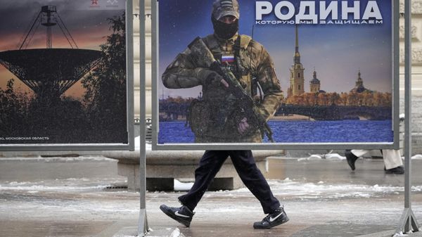 Мужчина проходит мимо стенда с изображением российского военнослужащего и надписью «Родина, которую мы защищаем» на уличной выставке военных фотографий в Санкт-Петербурге, Россия. - Sputnik Азербайджан