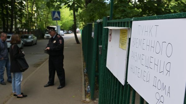  Сотрудник полиции у пункта временного размещения для жителей жилого дома, пострадавшего в результате атаки беспилотника, на улице Профсоюзная в Москве - Sputnik Азербайджан