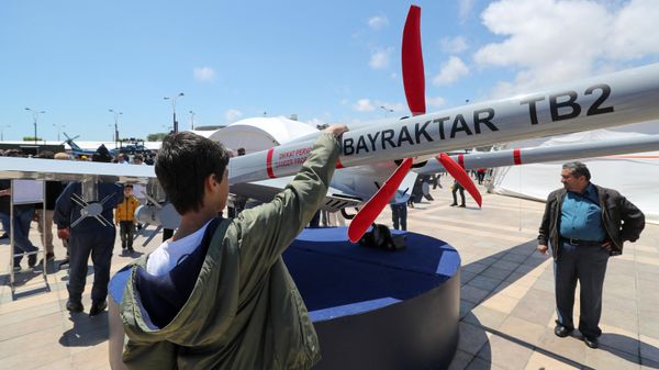Молодой человек смотрит на беспилотник Bayraktar TB2 производства турецкой компании Baykar - Sputnik Азербайджан