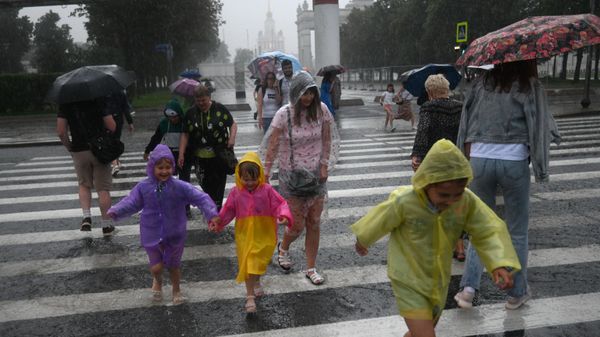 Люди переходят улицу по пешеходному переходу во время дождя в Москве - Sputnik Азербайджан