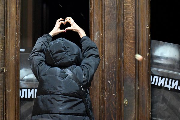 Демонстрант жестикулирует перед полицейскими, охраняющими вход в здание мэрии Белграда. - Sputnik Азербайджан