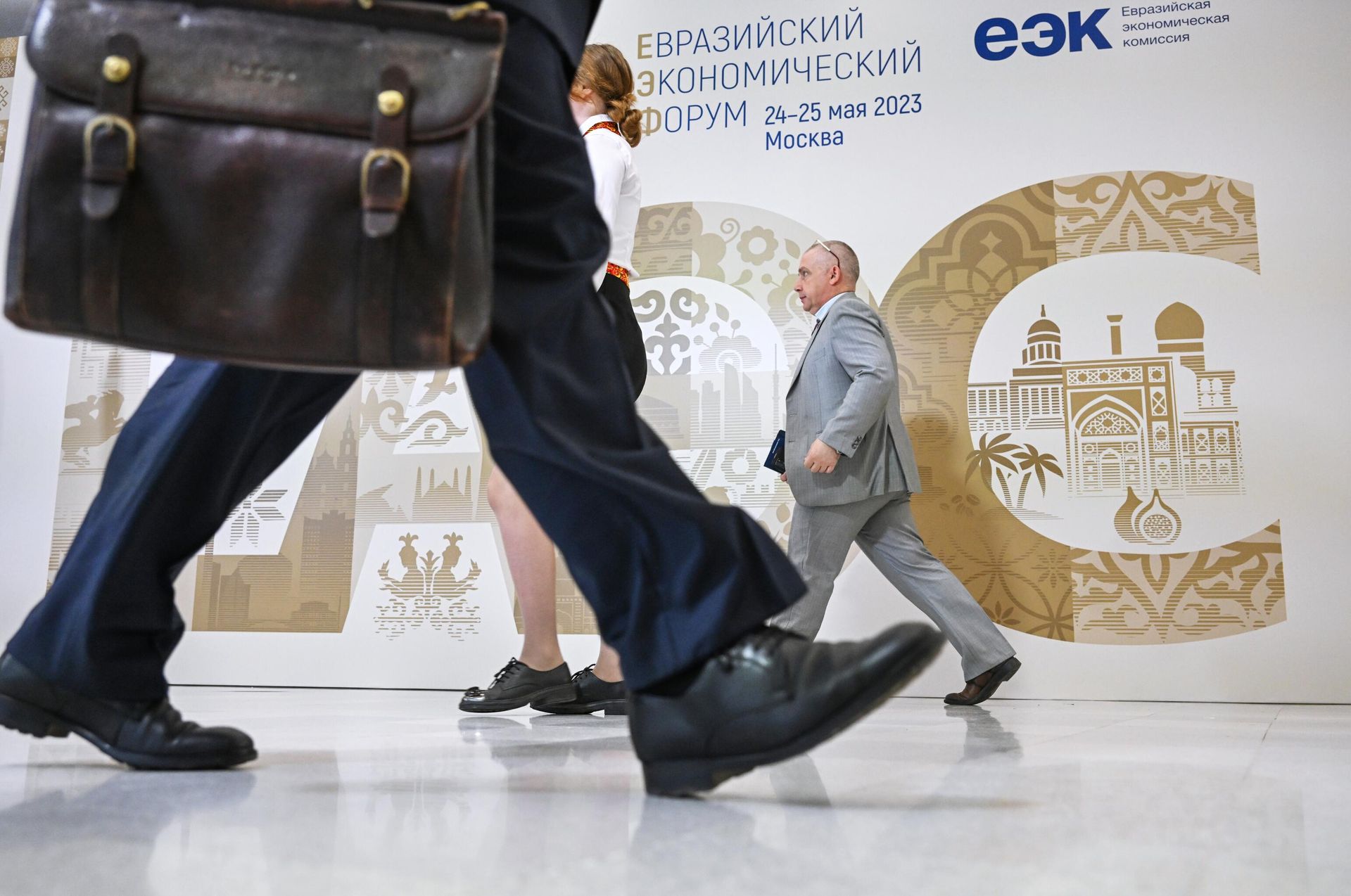 Участники проходят рядом со стендом с символикой Евразийского экономического форума - Sputnik Азербайджан, 1920, 23.05.2024