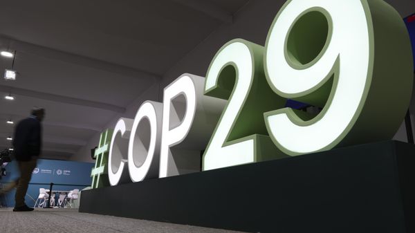 Участник идет возле знака климатического саммита COP29 в Баку - Sputnik Азербайджан
