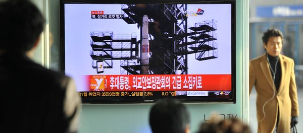 Туристы на железнодорожном вокзале в Сеуле смотрят новость о запуске ракеты - Sputnik Азербайджан