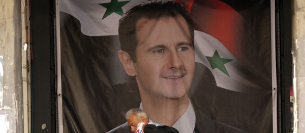 Мужчина проходит рядом с плакатом Башара Асада в столице Сирии Дамаске - Sputnik Азербайджан
