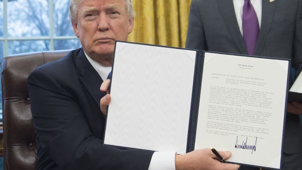Президент США Дональд Трамп держит в руках распоряжение о выводе США из Транс-Тихоокеанского партнерства после его подписания в Овальном кабинете Белого дома - Sputnik Азербайджан
