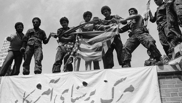 Люди с порванным флагом США стоят на крыше здания посольства Соединенных Штатов в ходе массовых антиамериканских демонстраций в Тегеране, 25 мая 1979 года - Sputnik Азербайджан