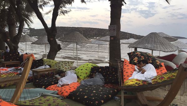 Мужчина лежит на берегу моря в Битезе, курортном поселке в 4 км от Бодрума, Турция, 21 июля 2017 года - Sputnik Азербайджан