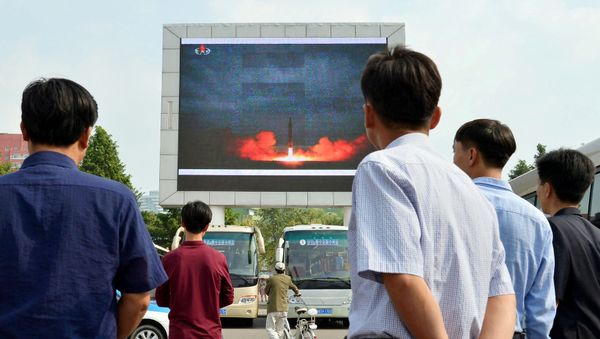Жители северокорейской столицы следят за новостями о запуске ракеты средней дальности Hwasong-12 на электронном табло в Пхеньяне, Северная Корея, 30 августа 2017 года - Sputnik Азербайджан