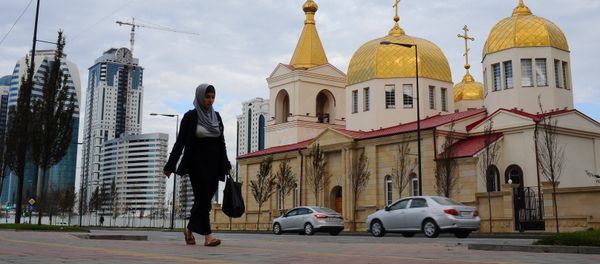 Женщина в хиджабе проходит по улице рядом с православной церковью Архангела Михаила на проспекте имени Ахмата Кадырова в Грозном, фото из архива - Sputnik Азербайджан