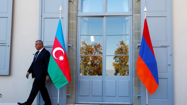 Охранник проходит мимо азербайджанского (слева) и армянского флага на открытии переговоров в Женеве, Швейцария - Sputnik Азербайджан