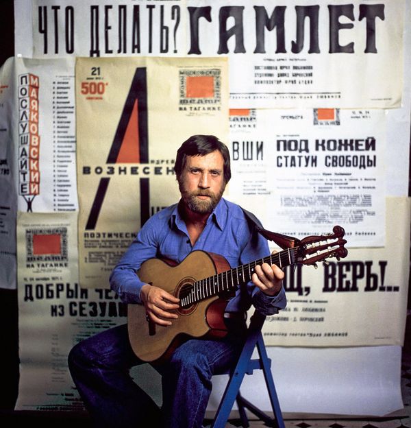 Актер и поэт Владимир Высоцкий (1938-1980) с гитарой на фоне афиш с репертуаром Театра на Таганке - Sputnik Азербайджан