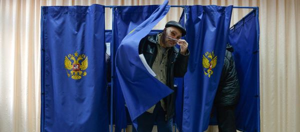 Мужчина выходит из кабинки во время голосования на выборах президента Российской Федерации на избирательном участке в Новосибирске - Sputnik Азербайджан