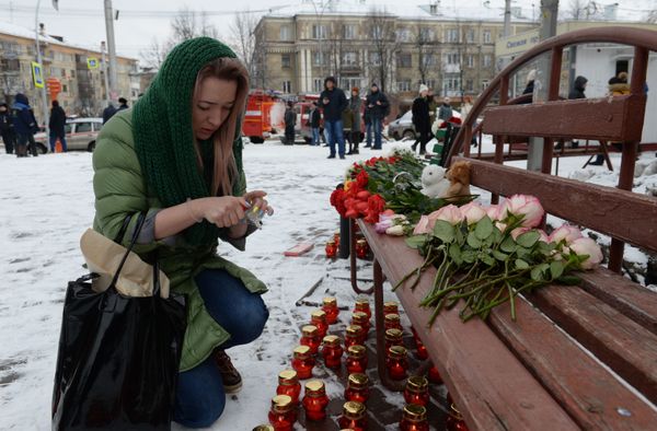 Женщина зажигает свечу возле здания торгового центра «Зимняя вишня» в Кемерово, где произошел пожар - Sputnik Азербайджан