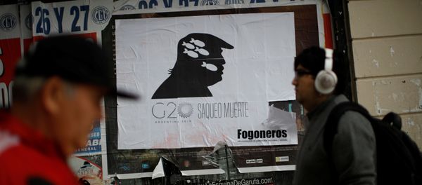Пешеходы проходят мимо знака с надписью G20, грабежи, смерть с изображением президента США Дональда Трампа на улице Буэнос-Айреса, Аргентина 1 декабря - Sputnik Азербайджан