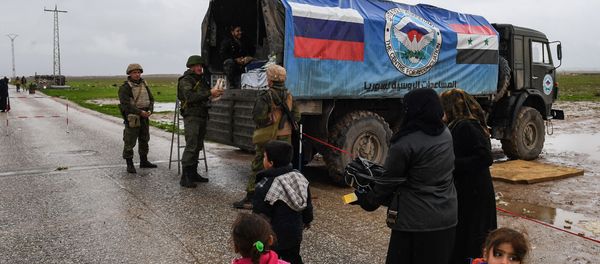 Сирийские гражданские лица проезжают мимо российского военного грузовика с продовольственной помощью - Sputnik Азербайджан