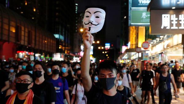 Протестующий против выдачи законопроекта поднимает маску Гая Фокса, когда он марширует в туристическом районе Гонконга Натан-роуд около Монгкока - Sputnik Азербайджан