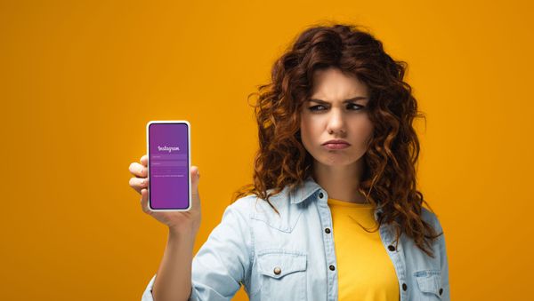 Красивая девушка хмурится и смотрит на смартфон с открытым приложением Instagram - Sputnik Азербайджан