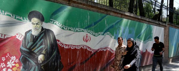 Люди проходят мимо фрески с изображением основателя исламской республики аятоллы Рухоллы Хомейни и государственного флага вдоль стены бывшего посольства США в иранской столице Тегеране 22 июня 2019 года - Sputnik Азербайджан