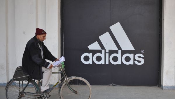 Мужчина едет на велосипеде перед логотипом Adidas, фото из архива - Sputnik Азербайджан