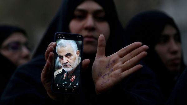 Женщина показывает фотографию убитого генерала Ирана Касема Сулеймани - Sputnik Азербайджан