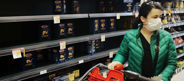 A woman wearing a protective face mask passes by a partly empty self of pasta as she shops in a super market in Athens, Greece - Sputnik Азербайджан