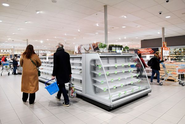 Shoppers walk by near-empty shelves at a supermarket in Amsterdam as people hoard food because of the coronavirus outbreak, - Sputnik Азербайджан