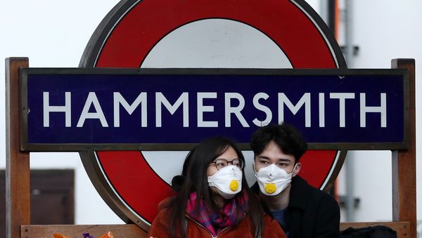 Пара в защитных масках у станции метро Hammersmith в Лондоне - Sputnik Азербайджан