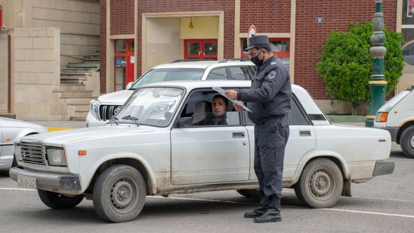 Ağstafada polis əməkdaşı sürücünün xüsusi rejim zamanı fəaliyyət göstərməsinə icazə verən sənədi yoxlayır - Sputnik Азербайджан