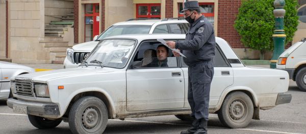 Ağstafada polis əməkdaşı sürücünün xüsusi rejim zamanı fəaliyyət göstərməsinə icazə verən sənədi yoxlayır - Sputnik Азербайджан