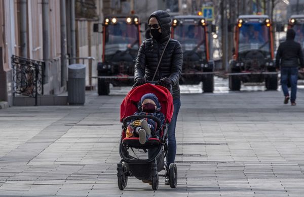 A mother wearing a protective mask pushes her baby's stroller in central Moscow on April 12, 2020 during a strict lockdown in Russia aimed a curbing the spread of the COVID-19 - Sputnik Азербайджан