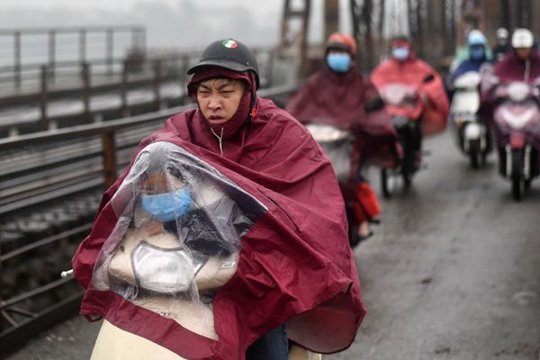 A child, wearing a facemask as a preventive measure against the COVID-19 novel coronavirus, rides under a rain cover on a scooter in Hanoi - Sputnik Азербайджан