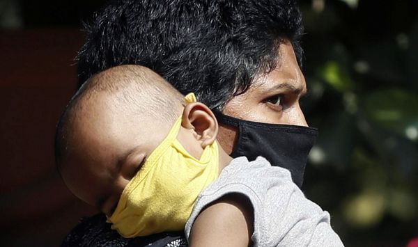 A person wearing a protective mask carries a child inside the premises of a hospital, where a special ward has been set up for treating the coronavirus disease, in Mumbai, India - Sputnik Азербайджан
