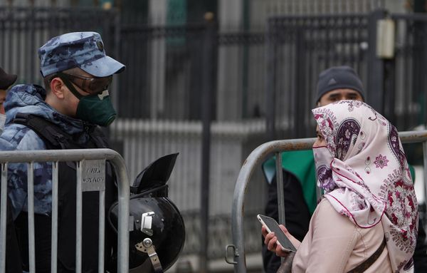 Сотрудник Росгвардии разговаривает с прохожей у Московской Соборной мечети, закрытой для посещений из-за риска распространения коронавирусной инфекции COVID-19 - Sputnik Азербайджан